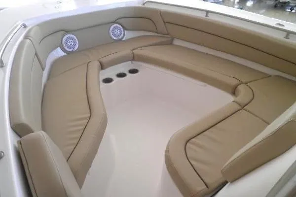 Slide: The Image of 2015 Tidewater 232 LXF boat interior with tan cushioned seating and built-in speakers. - 24