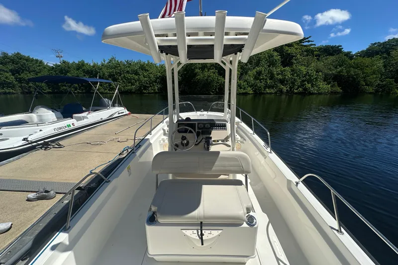 Slide: The Image of 2022 Boston Whaler 210 Montauk boat docked by a serene lake under a clear blue sky. - 6