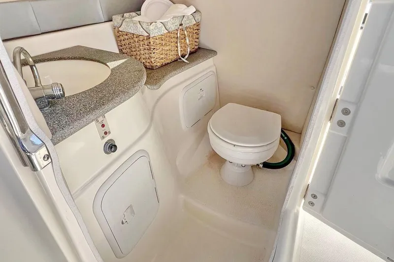 Slide: The Image of 2013 Larson LXi 292 IO boat bathroom with sink, toilet, and storage basket. - 17