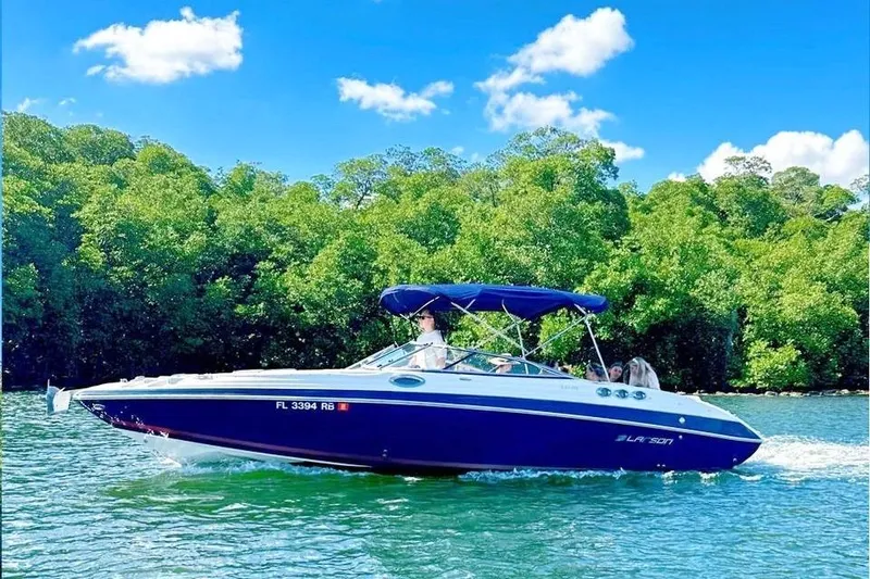 Slide: The Image of 2013 Larson LXi 292 IO boat cruising on a sunny day with lush greenery background. - 19