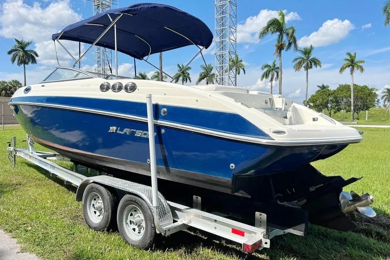 Slide: The Image of 2013 Larson LXi 292 IO boat on trailer, blue and white, parked on grass. - 4