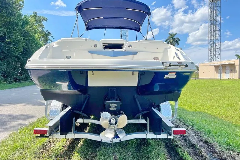 Slide: The Image of 2013 Larson LXi 292 IO boat on trailer, parked on grass under blue sky. - 5