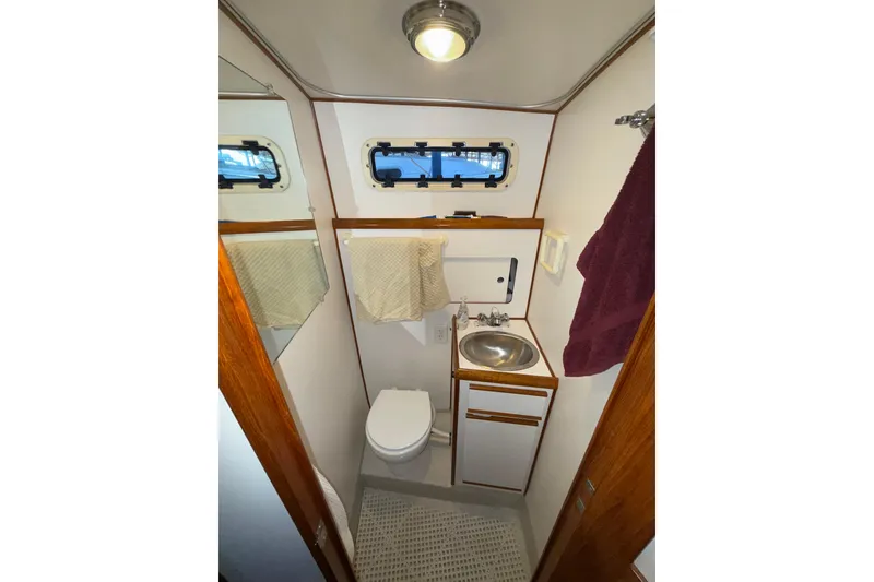 Slide: The Image of Compact bathroom in a 1997 Norstar 301 boat, featuring sink, toilet, and porthole window. - 13