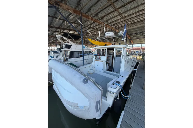 Slide: The Image of 1997 Norstar 301 boat docked in a marina, featuring a spacious deck and inflatable dinghy. - 3