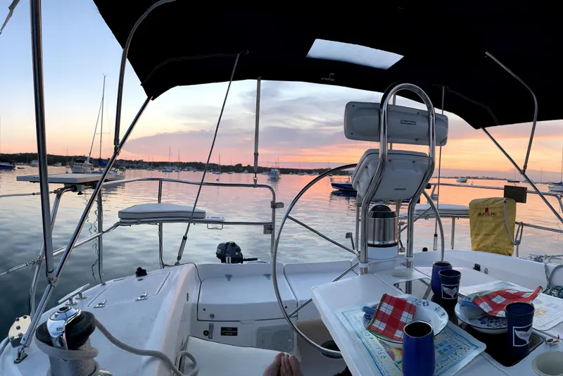 Slide: The Image of Cockpit view of 2001 Catalina 380 sailboat at sunset, with dining setup and scenic harbor. - 8