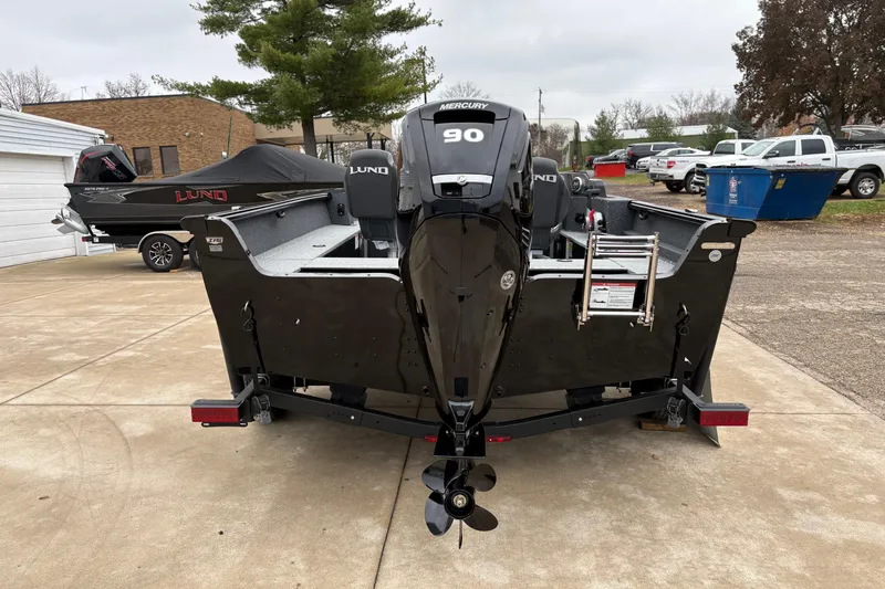 Slide: The Image of 2026 Lund 1700 Explorer SS boat with Mercury 90 engine, parked outdoors. - 2
