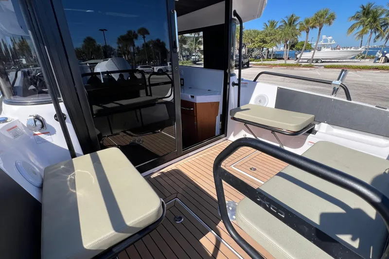 Slide: The Image of 2024 XO Boats EXPLR 10 S Plus interior with seating and teak flooring, docked near palm trees. - 17
