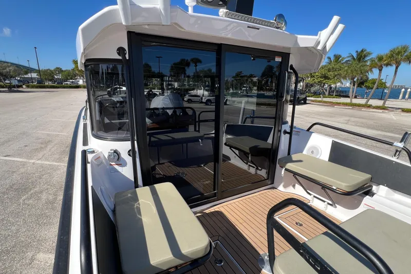 Slide: The Image of 2024 XO Boats EXPLR 10 S Plus, docked with seating and glass doors, sunny day. - 18