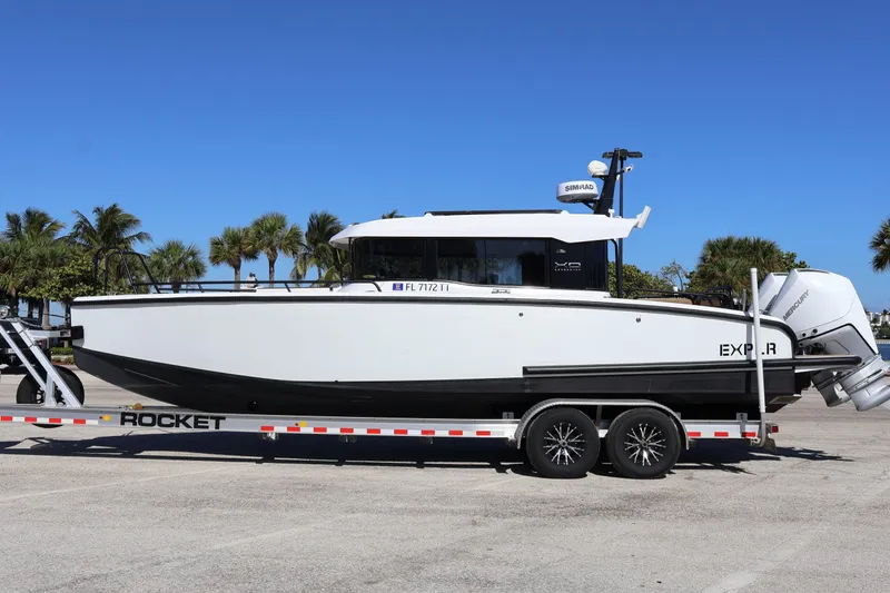 Slide: The Image of 2024 XO Boats EXPLR 10 S Plus on trailer, parked with palm trees in background. - 6