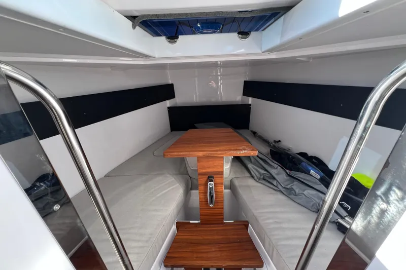 Slide: The Image of 2024 XO Boats EXPLR 10 S Plus cabin interior with wooden table and cushioned seating. - 63