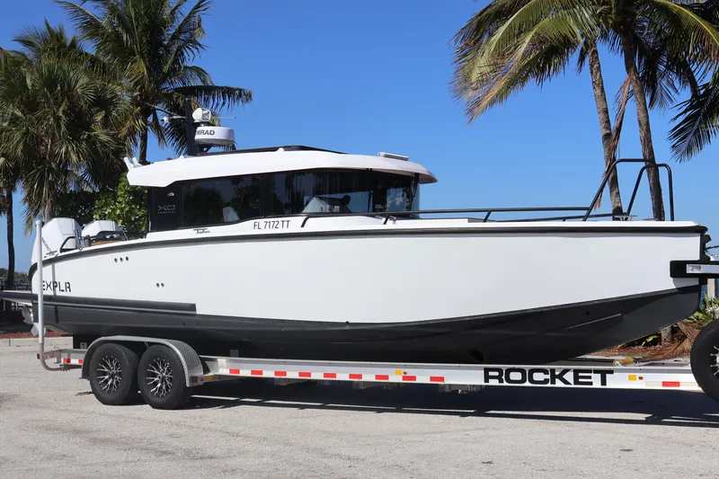 Slide: The Image of 2024 XO Boats EXPLR 10 S Plus on trailer, palm trees in background. - 7