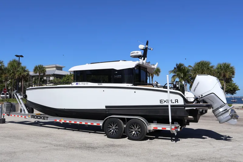 Slide: The Image of 2024 XO Boats EXPLR 10 S Plus on trailer, parked outdoors under clear blue sky. - 9