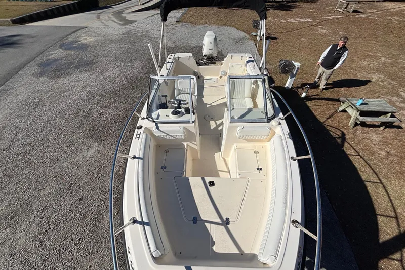 Slide: The Image of 2004 Key West 2020 Dual Console boat on land, with a person nearby. - 20