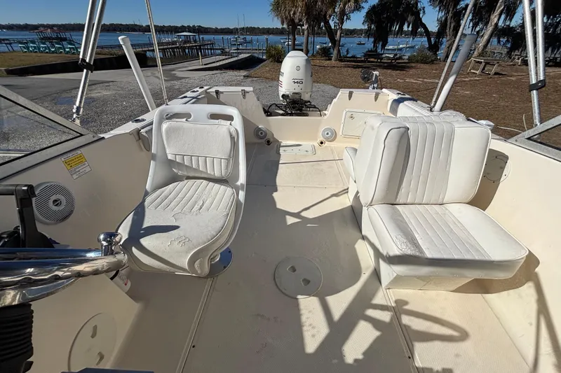 Slide: The Image of 2004 Key West 2020 Dual Console boat interior with white seating and outboard motor. - 8