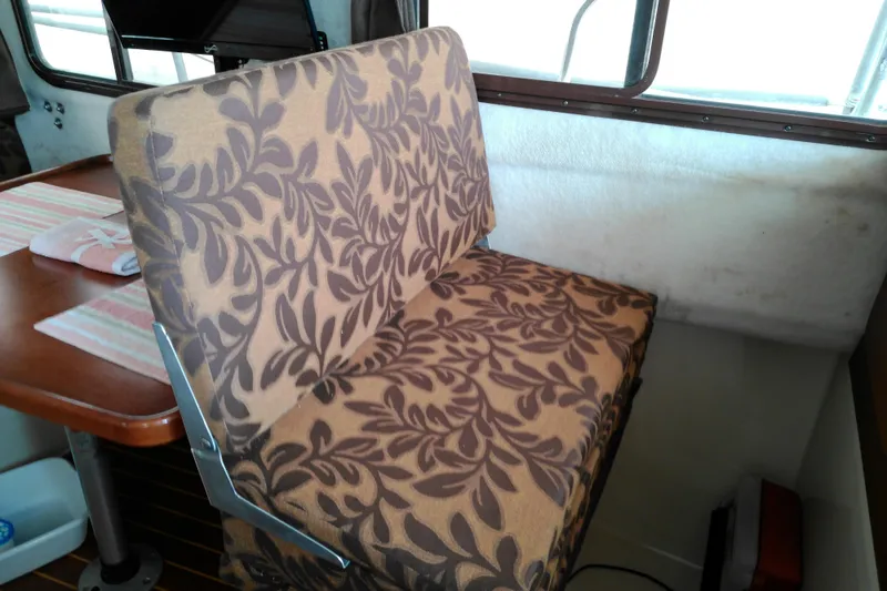 Slide: The Image of 2010 Ranger Tugs R-25 interior with floral-patterned seat and wooden table. - 14