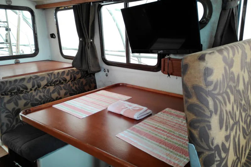 Slide: The Image of Interior of 2010 Ranger Tugs R-25 with dining area, TV, and patterned upholstery. - 15