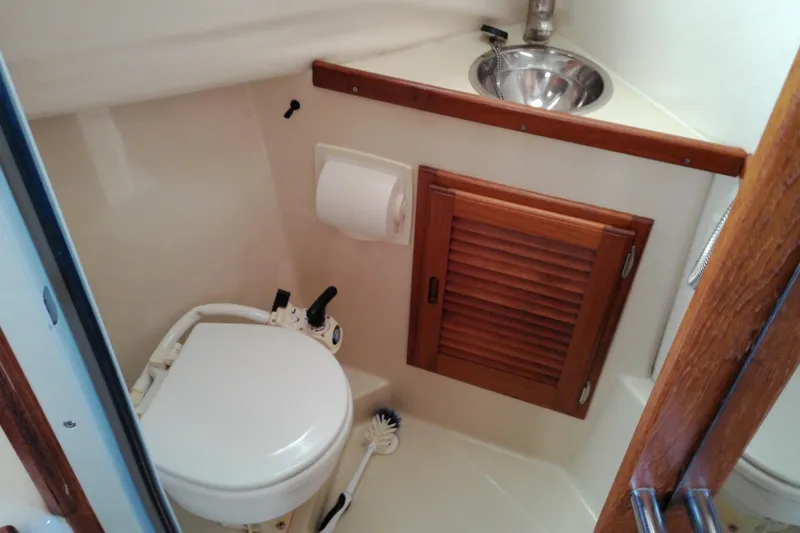 Slide: The Image of 2010 Ranger Tugs R-25 boat bathroom with toilet, sink, and wooden cabinet. - 30