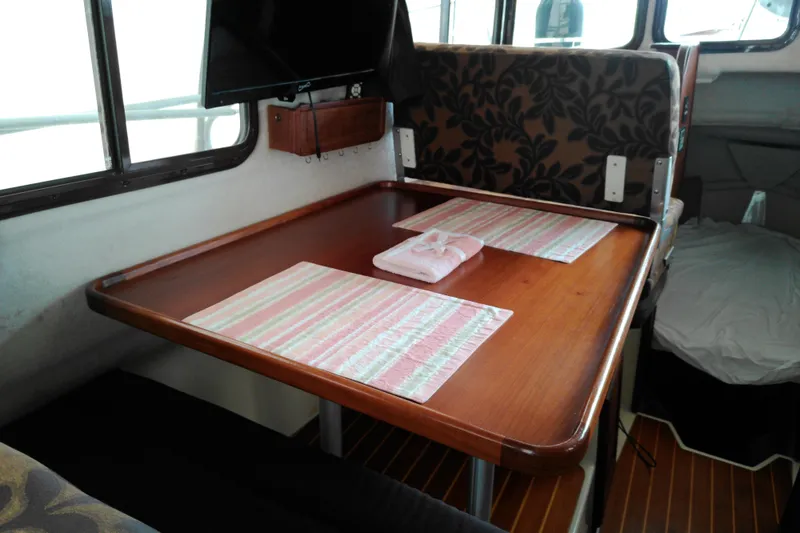 Slide: The Image of 2010 Ranger Tugs R-25 interior dining area with wooden table and patterned seating. - 8