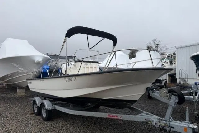Slide: The Image of 2017 Boston Whaler 190 Montauk boat on trailer, parked outdoors with protective cover nearby. - 1
