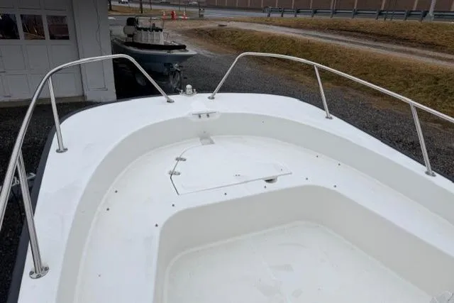 Slide: The Image of 2017 Boston Whaler 190 Montauk boat deck, featuring spacious white interior and stainless steel railings. - 7