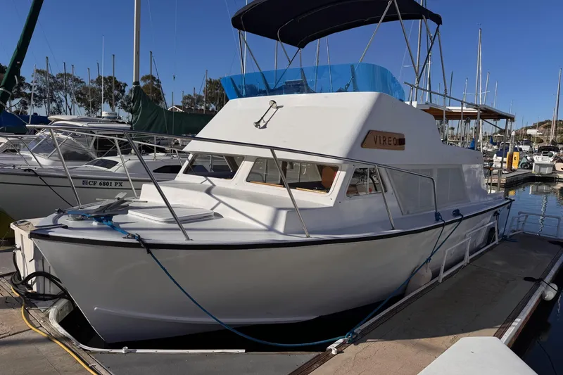 The Image of 1972 Gandy Flybridge boat docked at marina, featuring sleek white design and blue canopy. - 0