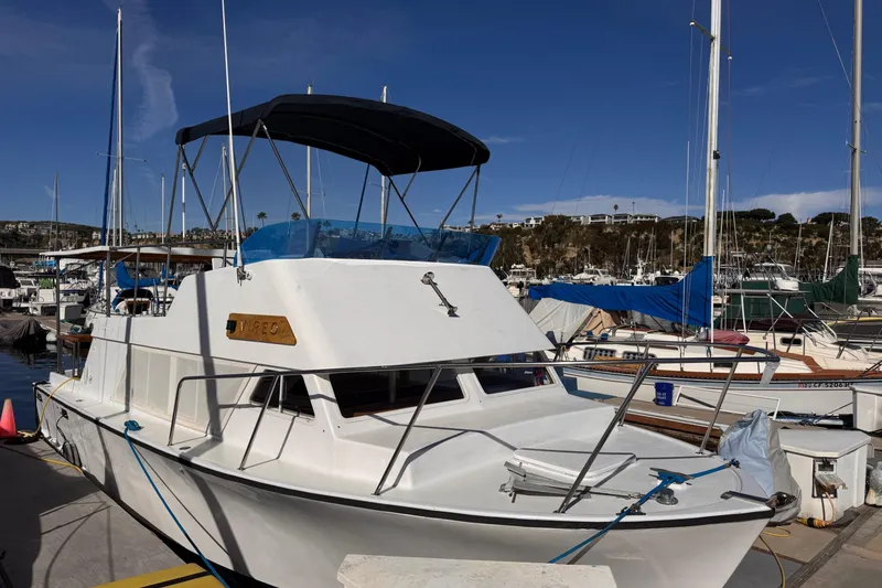 Slide: The Image of 1972 Gandy Flybridge boat docked at a marina under a clear blue sky. - 2