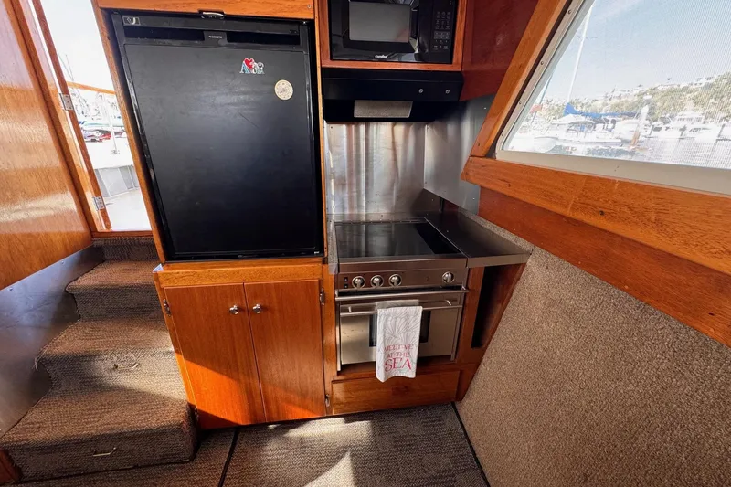 Slide: The Image of 1972 Gandy Flybridge kitchen with fridge, stove, and microwave, featuring wood cabinetry and marina view. - 20