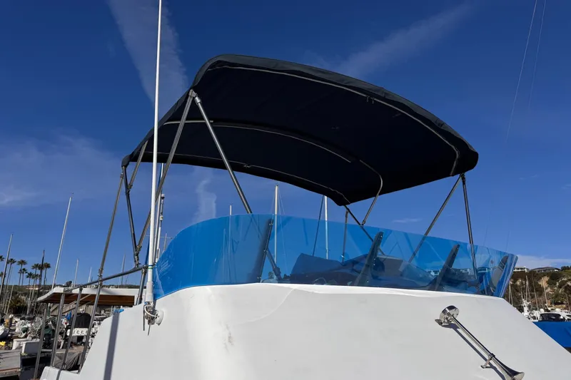 Slide: The Image of 1972 Gandy Flybridge boat with blue canopy and windshield, docked under clear sky. - 5