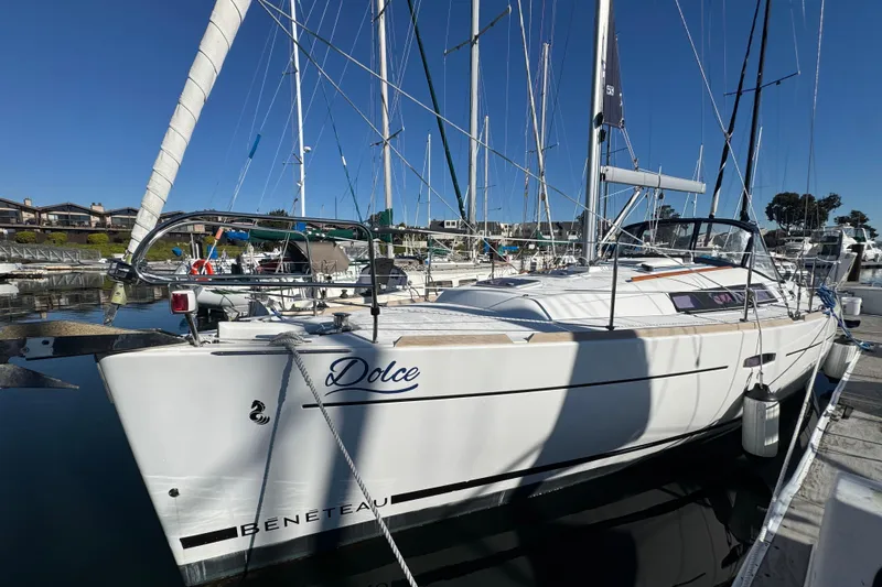 The Image of 2014 Beneteau Oceanis 34 sailboat docked in marina, clear blue sky background. - 1