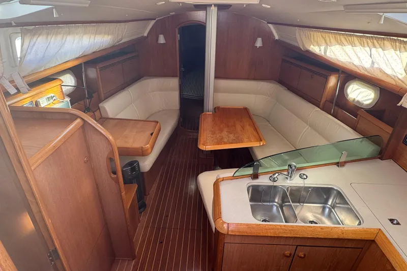 Slide: The Image of Interior of 2004 Jeanneau Sun Fast 35 sailboat with wood finish and cozy seating area. - 13