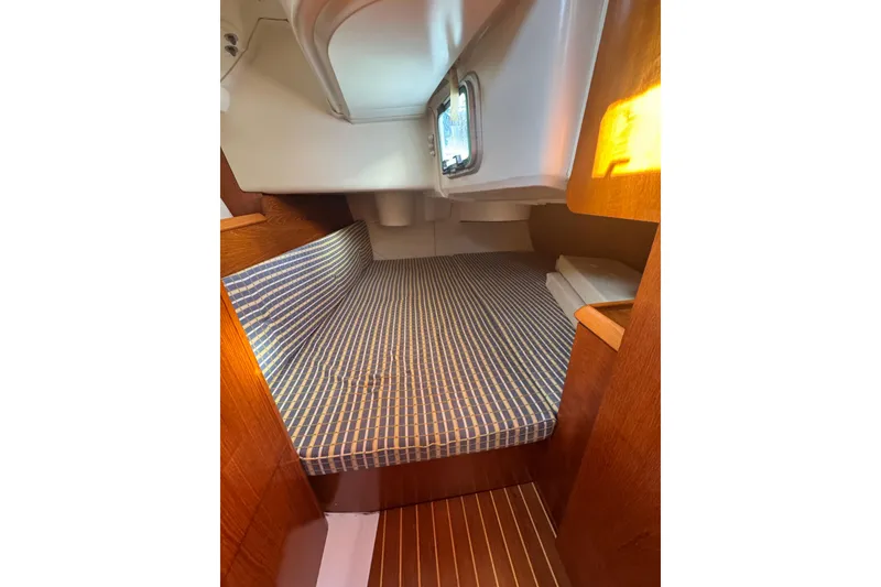 Slide: The Image of 2004 Jeanneau Sun Fast 35 cabin interior with striped bedding and wooden finish. - 21