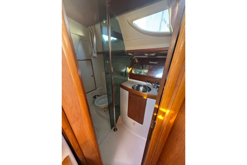 Slide: The Image of 2004 Jeanneau Sun Fast 35 yacht bathroom with sink, toilet, and wooden cabinetry. - 22