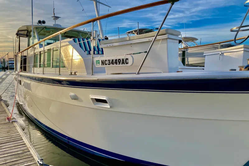 Slide: The Image of 1971 Hatteras 43 Double Cabin yacht docked at sunset, reflecting on water. - 12