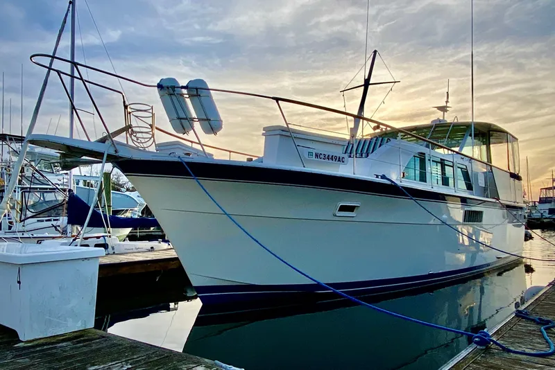 Slide: The Image of 1971 Hatteras 43 Double Cabin yacht docked at sunset, featuring lifebuoys and nautical equipment. - 2