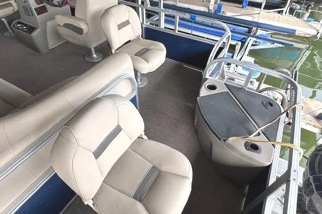 Slide: The Image of 2024 Sun Tracker Bass Buggy 18 DLX interior with seating and helm, docked by water. - 13