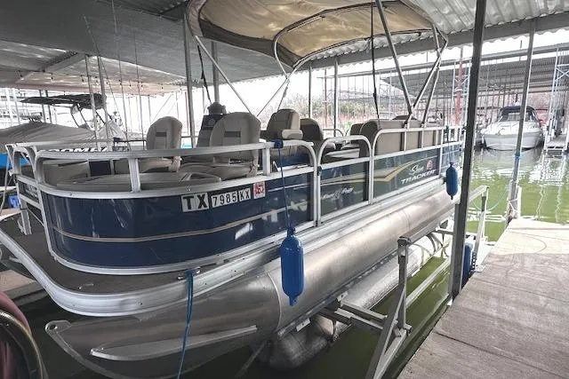 Slide: The Image of 2024 Sun Tracker Bass Buggy 18 DLX pontoon boat docked in a marina. - 2