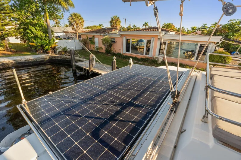 Slide: The Image of 2019 Fountaine Pajot 47 catamaran with solar panels docked near a waterfront home. - 13