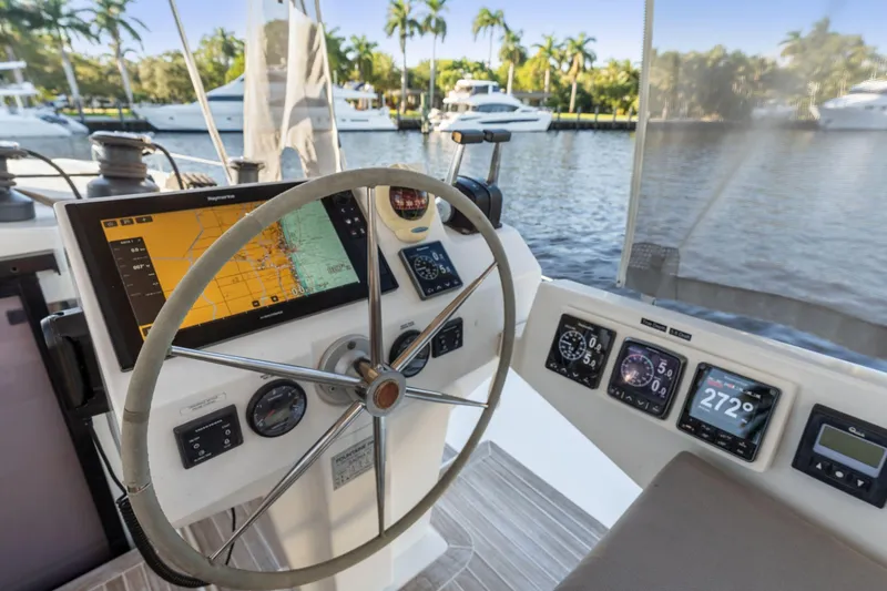Slide: The Image of Helm of 2019 Fountaine Pajot 47 catamaran with navigation instruments and scenic marina view. - 32