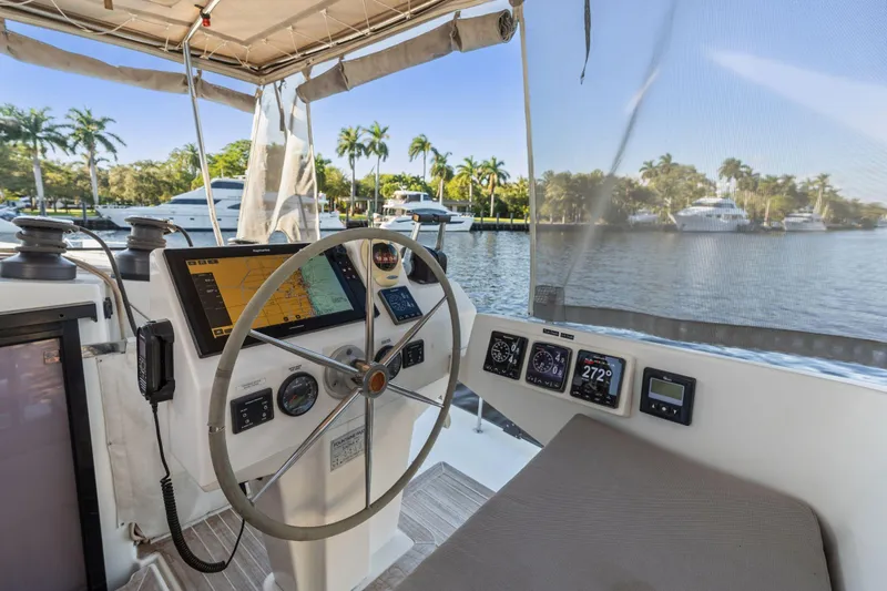 Slide: The Image of Helm of 2019 Fountaine Pajot 47 catamaran with navigation equipment, docked by palm trees. - 35