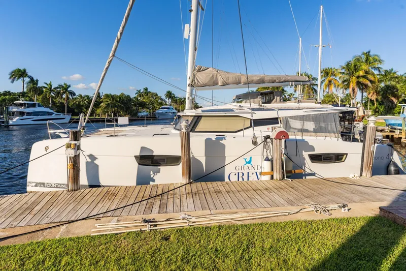 Slide: The Image of 2019 Fountaine Pajot 47 catamaran docked, surrounded by palm trees and clear blue sky. - 4