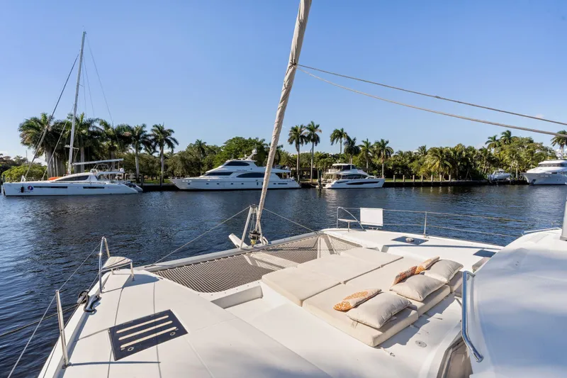 Slide: The Image of 2019 Fountaine Pajot 47 catamaran on tranquil waterway with palm trees and yachts. - 5