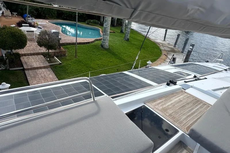 Slide: The Image of 2019 Fountaine Pajot 47 yacht with solar panels, docked near a poolside garden. - 6