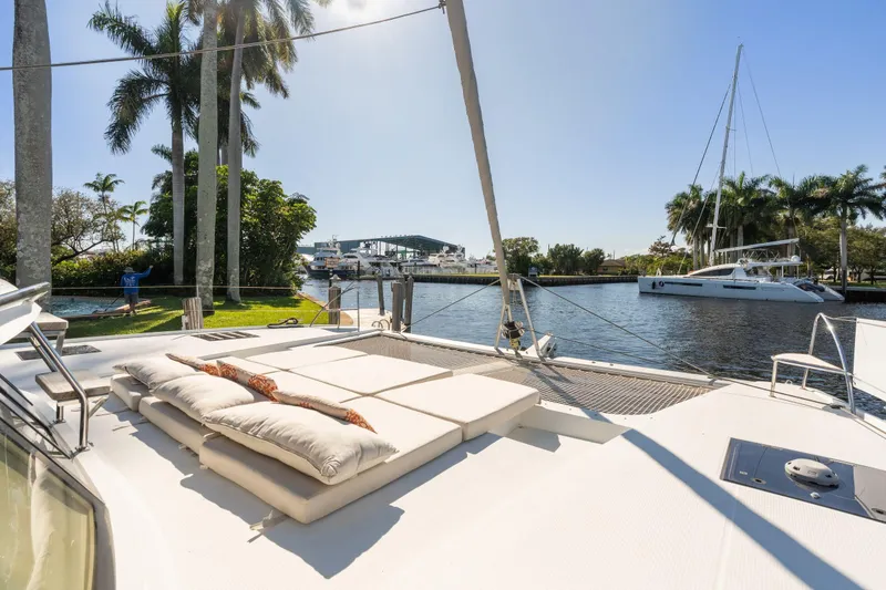 Slide: The Image of 2019 Fountaine Pajot 47 catamaran with sunbathing area, docked near palm trees and waterway. - 7