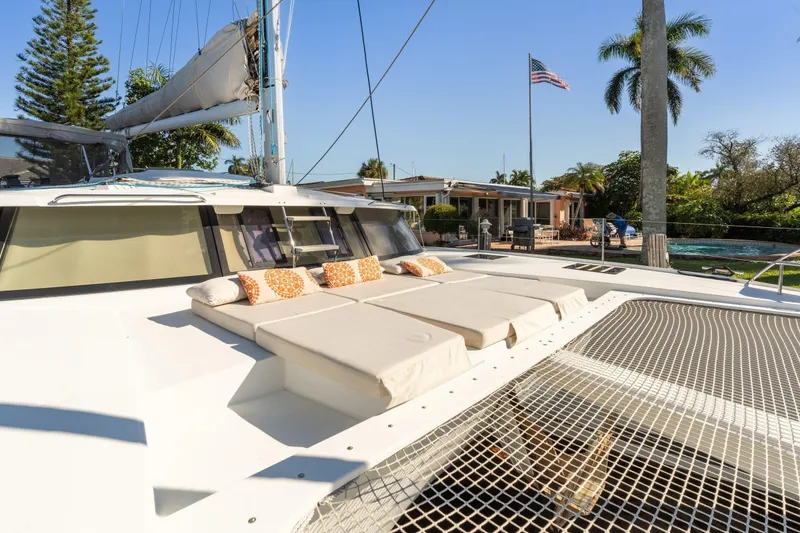Slide: The Image of 2019 Fountaine Pajot 47 catamaran with sunbathing area and netting, docked near a tropical setting. - 9