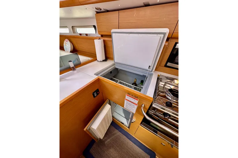 Slide: The Image of Jeanneau Sun Odyssey 409 yacht kitchen with open fridge, stove, and modern wood finish. - 46