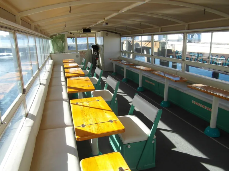 Slide: The Image of Interior of 2005 Trident 40 Passenger Tour Boat with wooden tables and cushioned seating. - 5