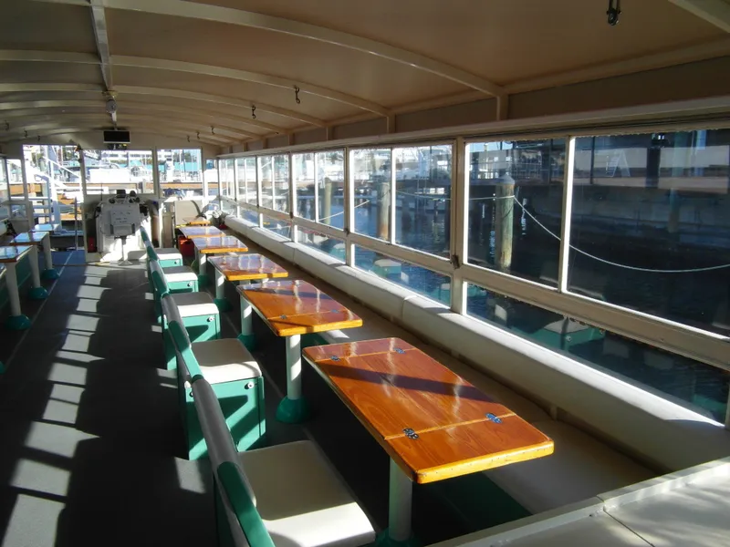 Slide: The Image of Interior of 2005 Trident 40 Passenger Tour Boat with wooden tables and seating. - 6