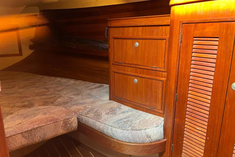 Slide: The Image of 1995 Island Packet 37 sailboat interior with wooden cabinetry and cushioned berth. - 16