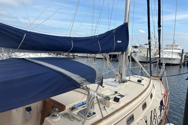Slide: The Image of 1995 Island Packet 37 sailboat docked, featuring blue sail covers and rigging. - 9
