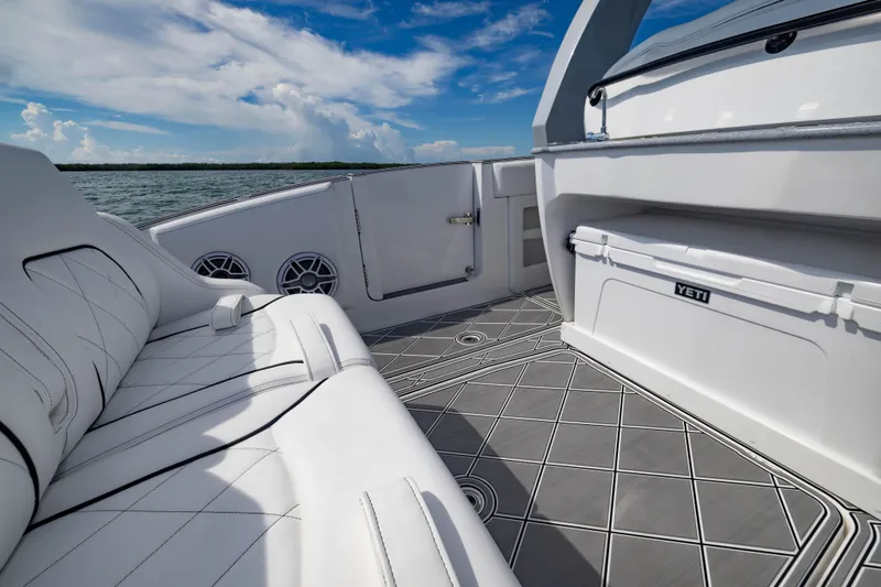 Slide: The Image of 2024 Deep Impact 399 Sport boat interior with luxury seating and Yeti cooler on deck. - 49